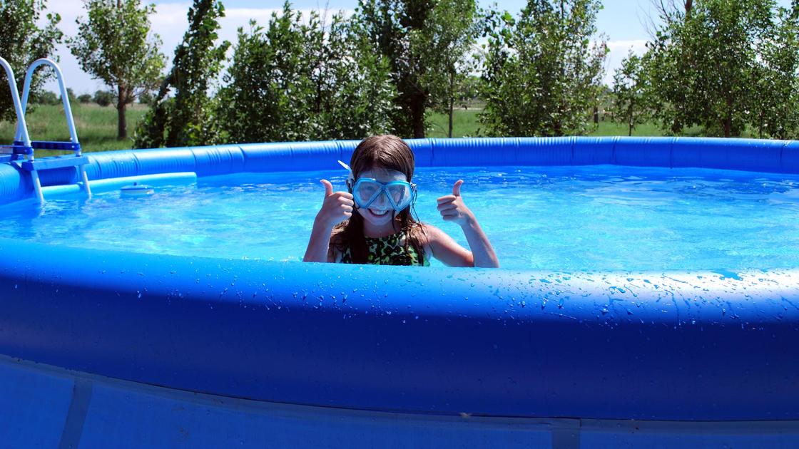 Девочка купается в бассейне
