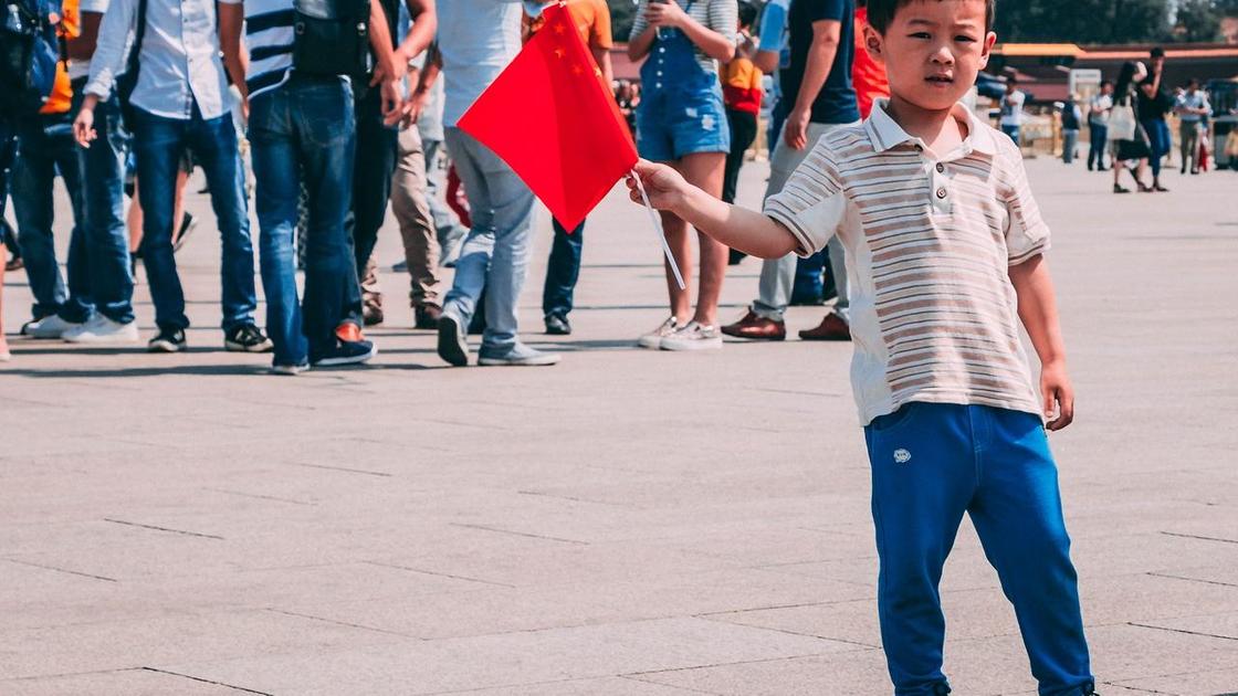 Мальчик стоит на улице с флагом Китая