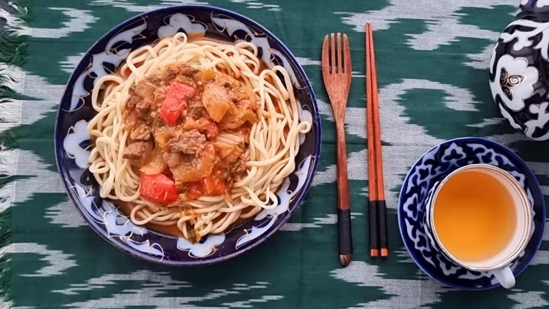 На тарелке уйгурский лагман. Ряжом чашка с чаем