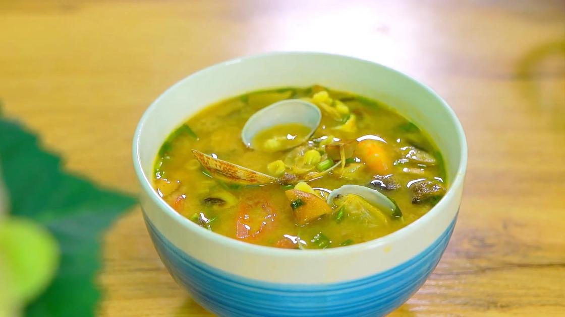 В глубокой сервировочной тарелке суп с морепродуктами: креветками и ракушками вонголе
