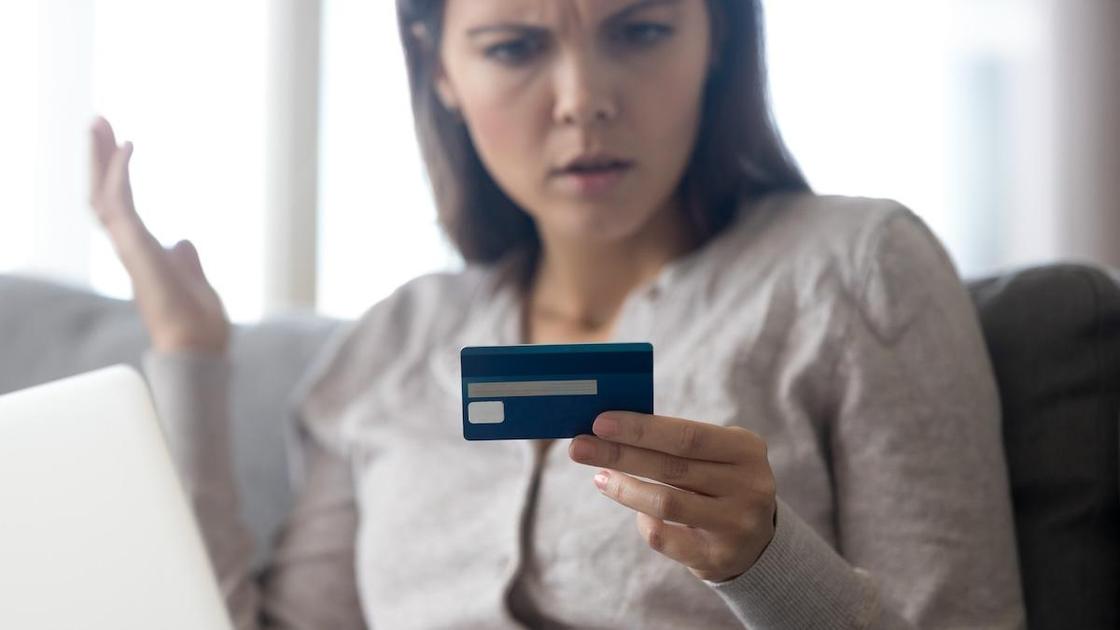 Женщина смотрит на кредитную карточку