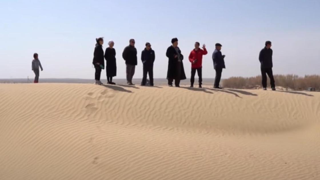 Несколько людей стоят на песчаном бархане