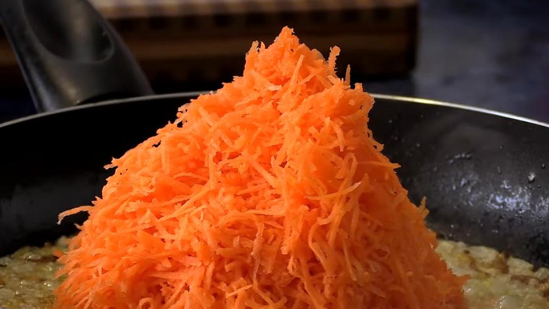 Тертая морковь на сковороде с обжаренным луком