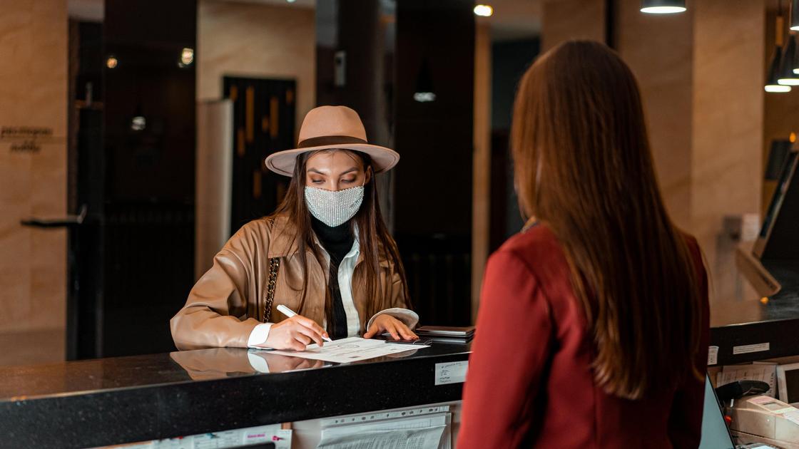 Девушка подписывает документы при въезде в отель