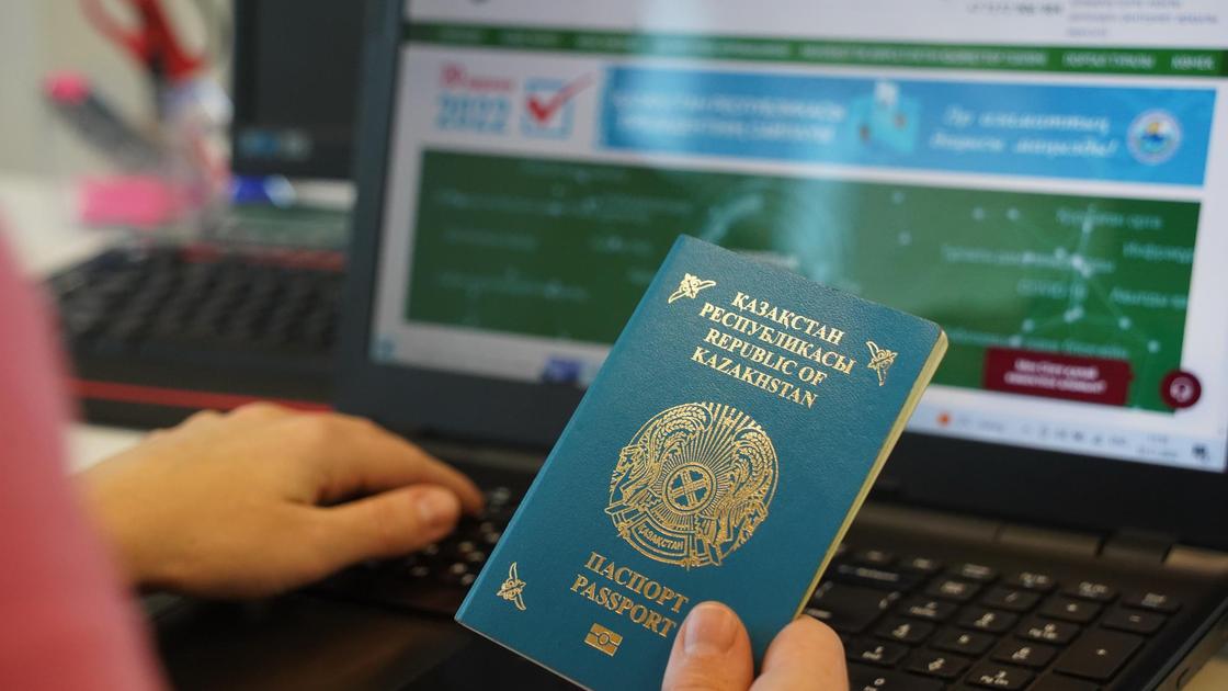 Открытый сайт eGov на ноутбуке и паспорт РК в руке