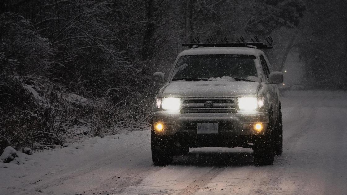 Автомобиль Toyota стоит на дороге зимой с включенными фарами