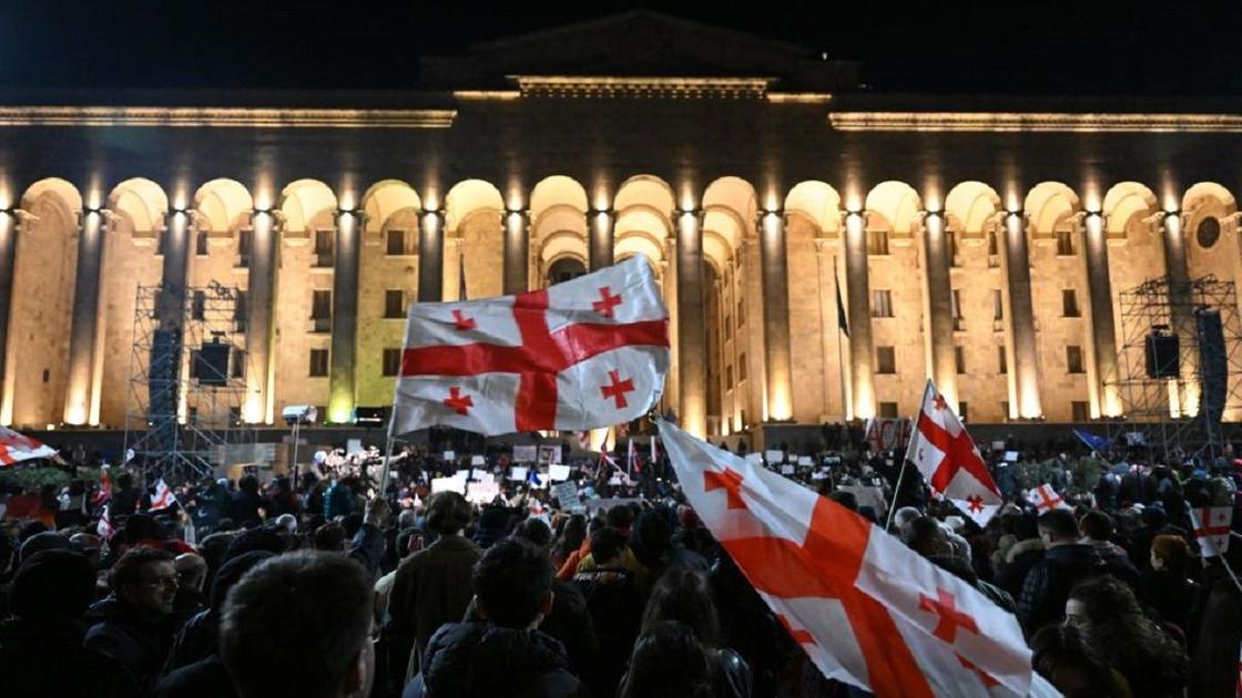 Протестующие люди на улице с флагами Грузии