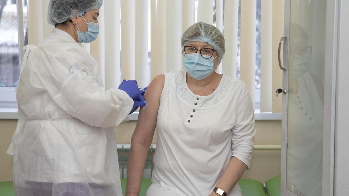 Медсестра делает прививку женщине в очках
