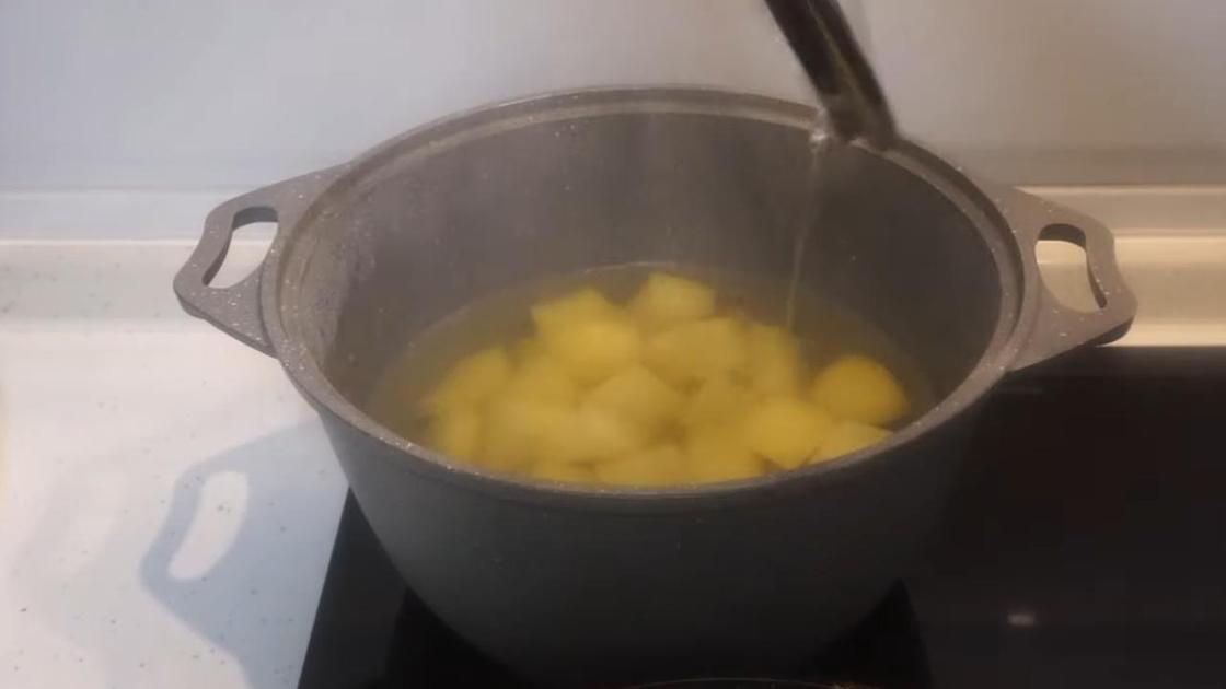 В кастрюле на плите дольки картофеля