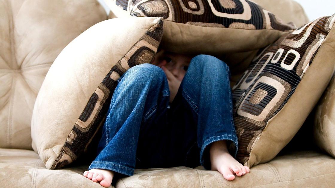 мальчик спрятался под подушками на диване