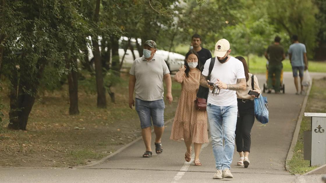Люди в масках идут по улице в Алматы
