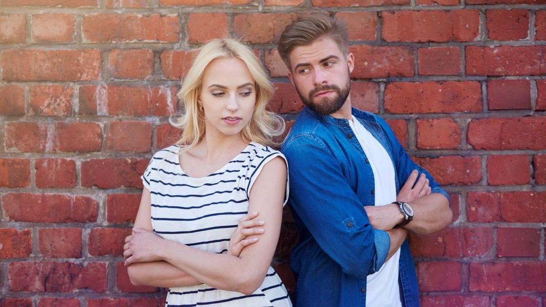 Chlap a dívka stojí poblíž cihlové zdi