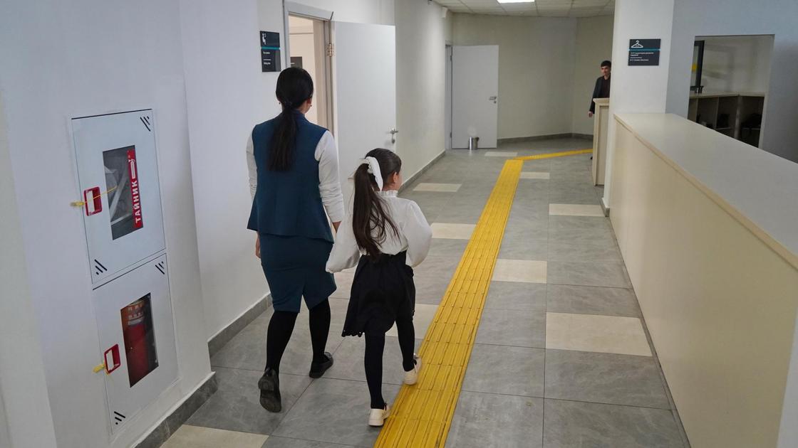 Учитель идет с ученицей по коридору