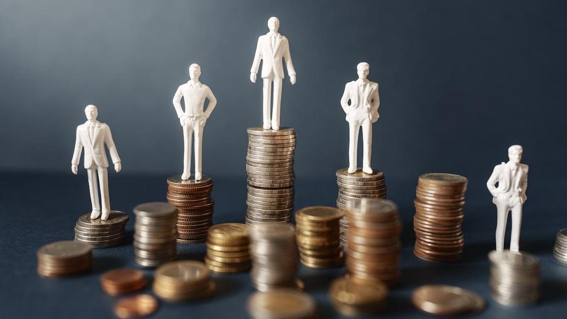 Фигурки людей стоят на столбиках монет