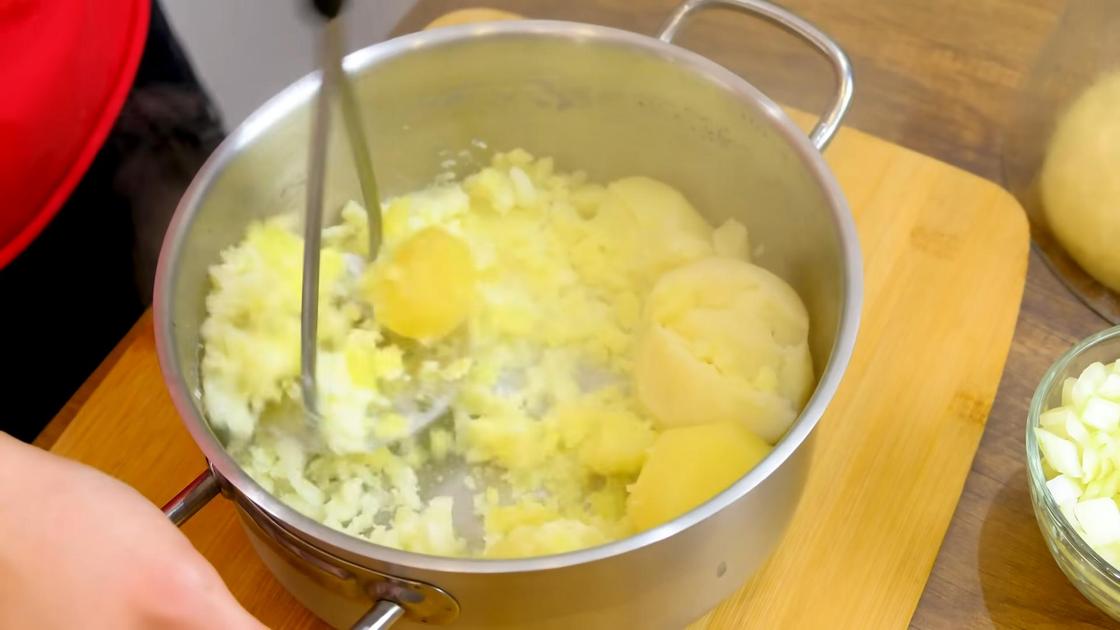 Вареный картофель в кастрюле разминают металлической толкушкой в пюре