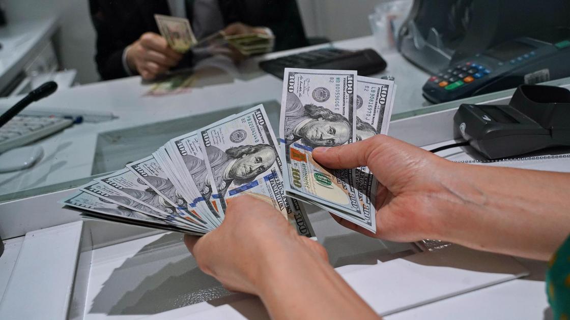 Женщина покупает доллары в банковской кассе