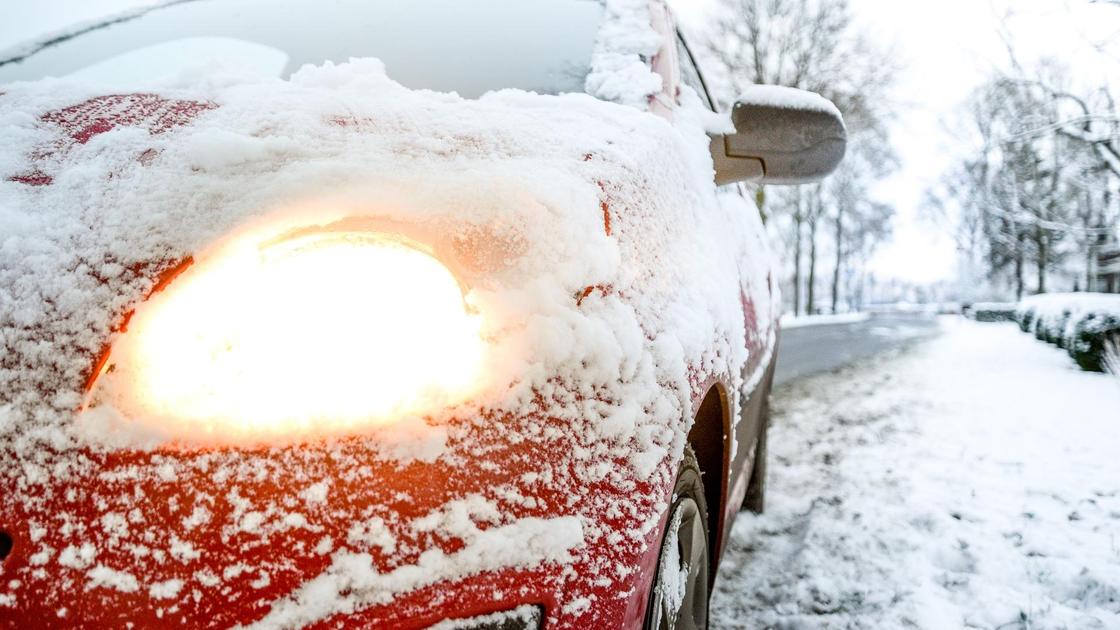 засыпанная снегом машина стоит на дороге
