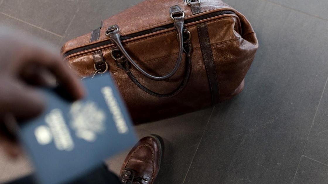 Человек держит в руках паспорт синего цвета