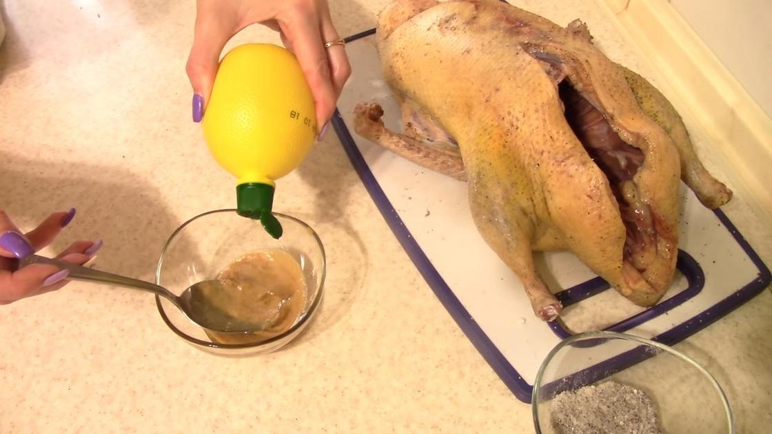 Приготовление маринада для утки, лежащей на разделочной доске. В пиалу к горчице добавляют лимонный сок