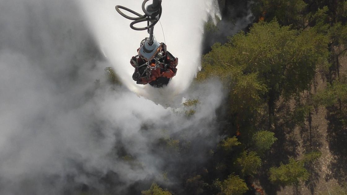 Вертолет сбрасывает воду на горящий лес