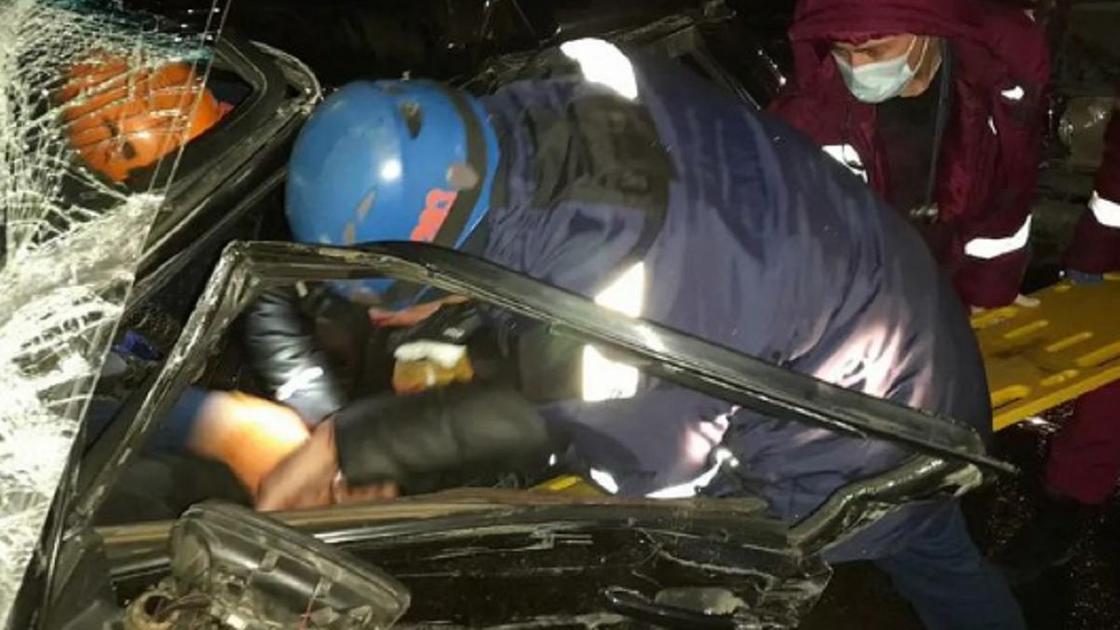 Спасатели помогают выбраться людям, зажатым в машине