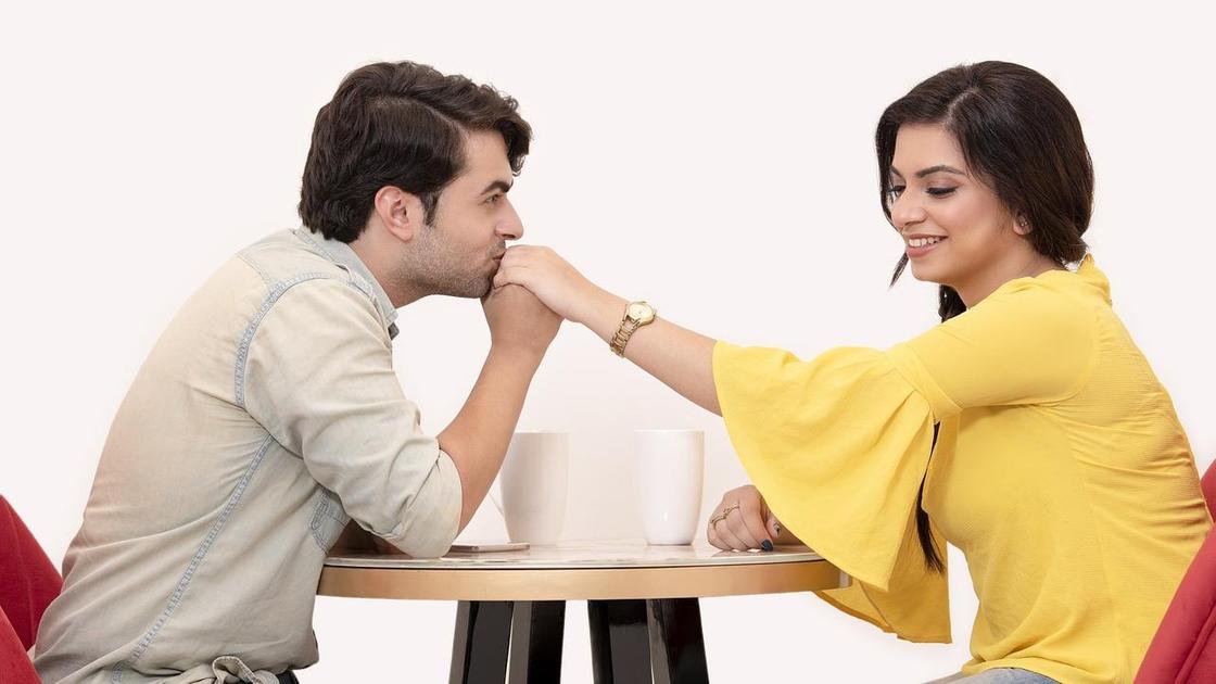Мужчина за столиком целует девушке руку