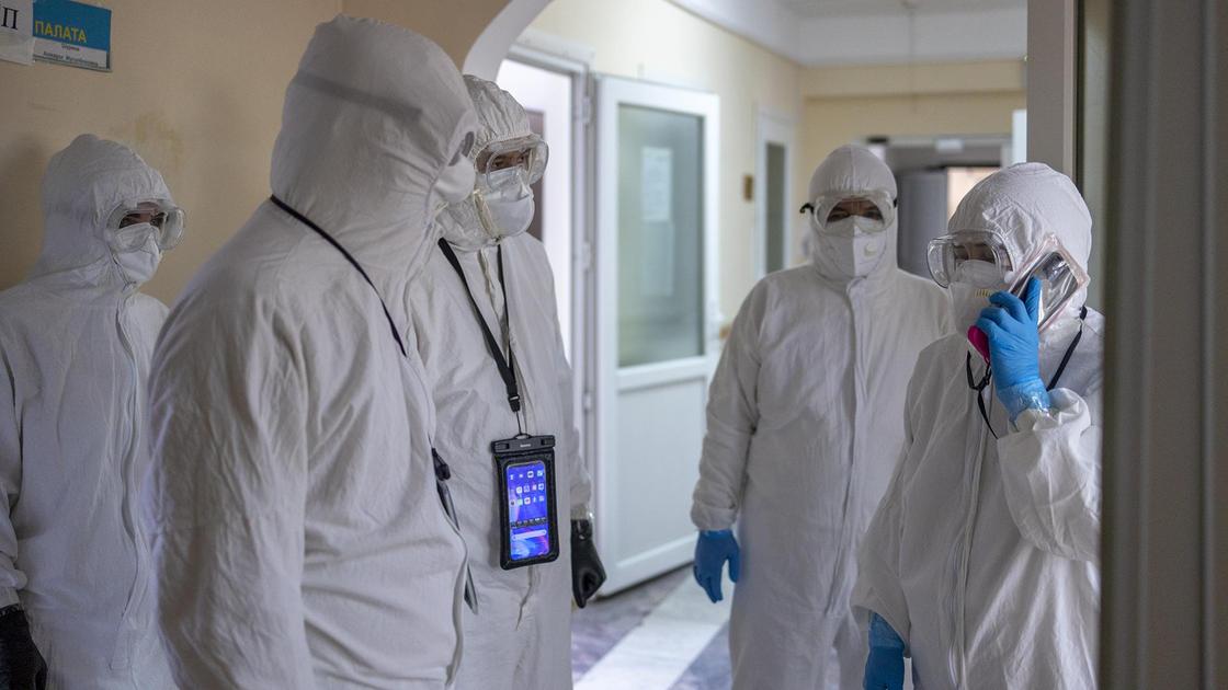 Медики в защитных костюмах стоят в коридоре больницы