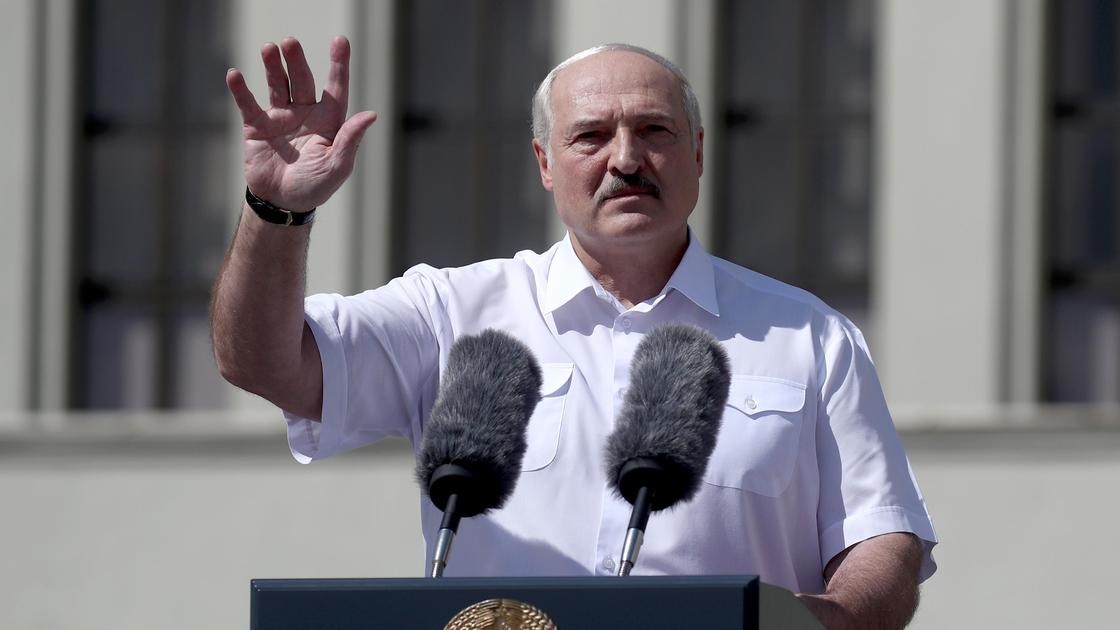 Александр Лукашенко стоит за трибуной