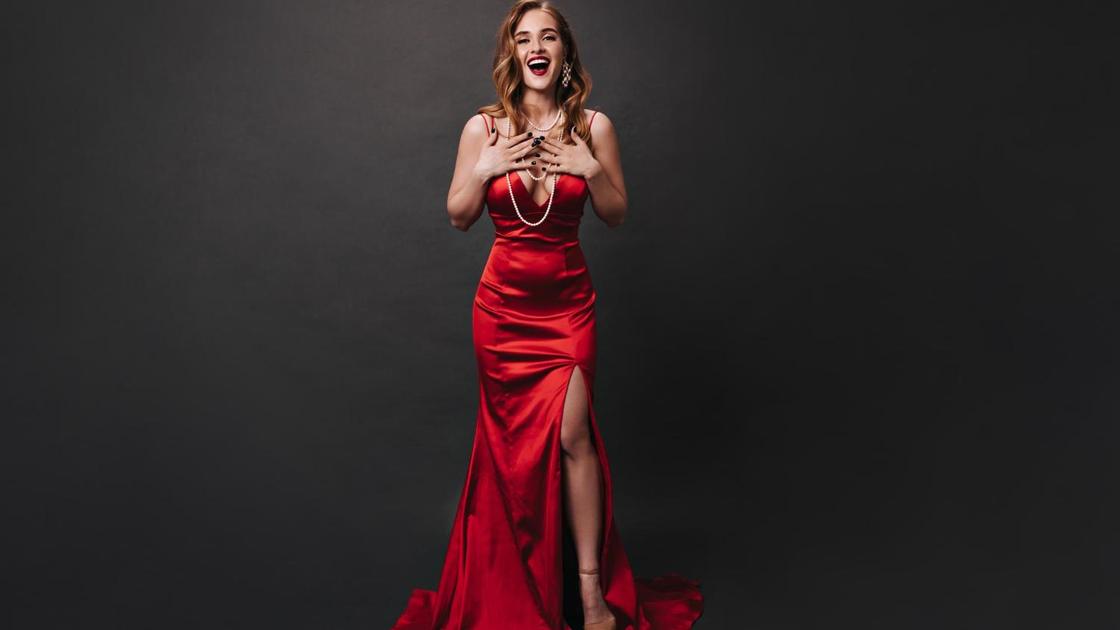 Красивая девушка в красном атласном вечернем платье