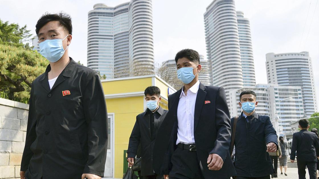 Люди в масках идут по Пхеньяну