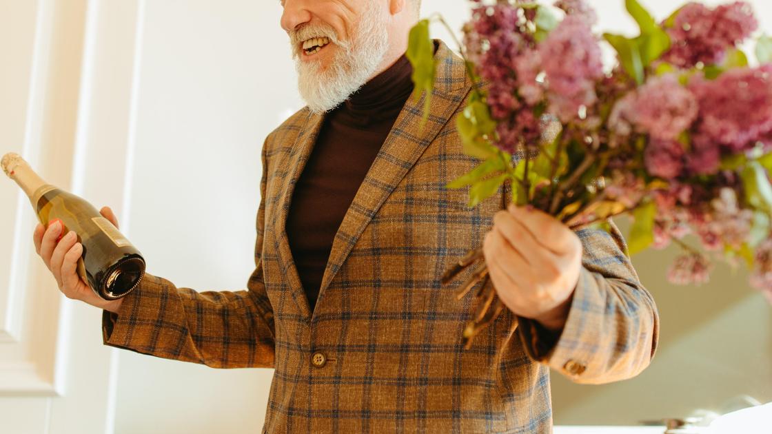 Мужчина с шампанским и цветами в руках