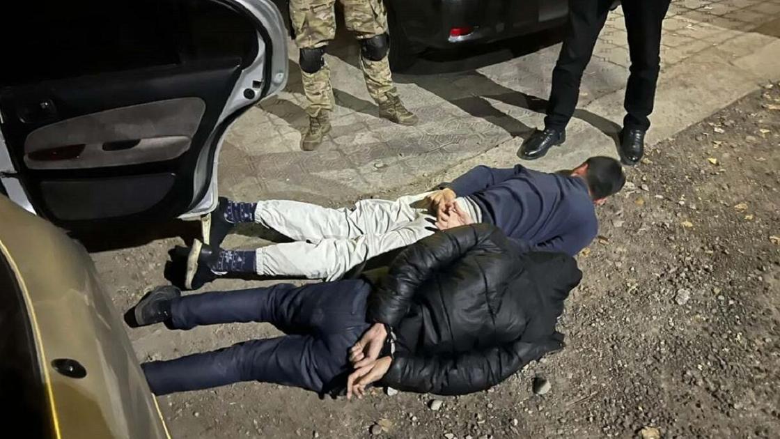 Полиция стоит у задержанных, которые лежат на земле