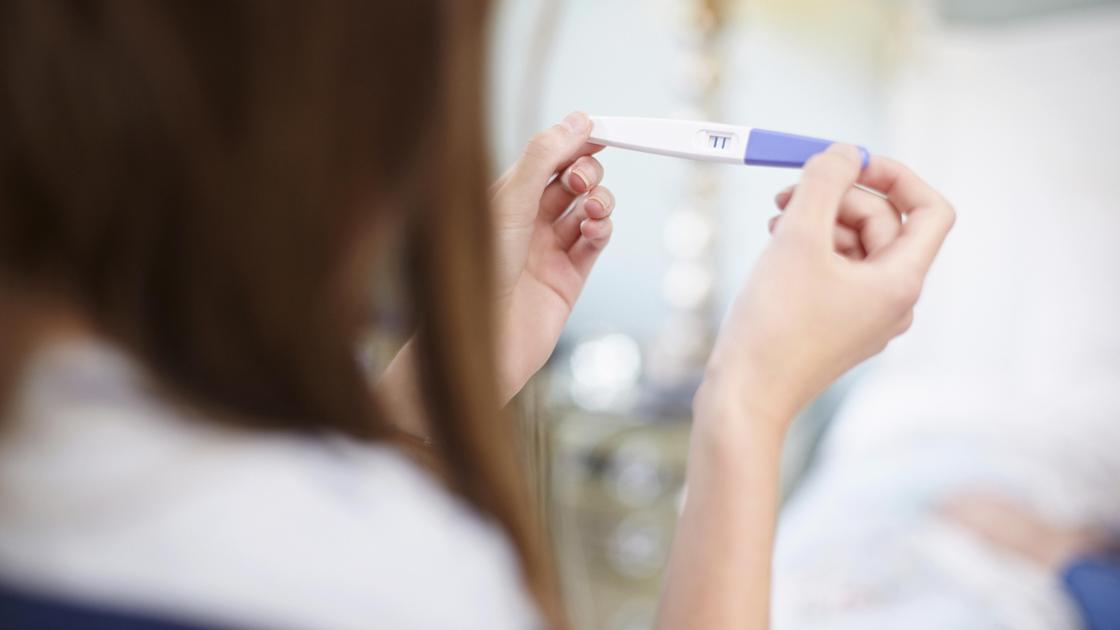 Девушка смотрит на результат теста на беременность