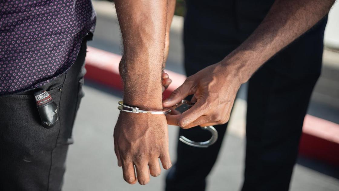 Полицейский надевает наручники на руки задержанного
