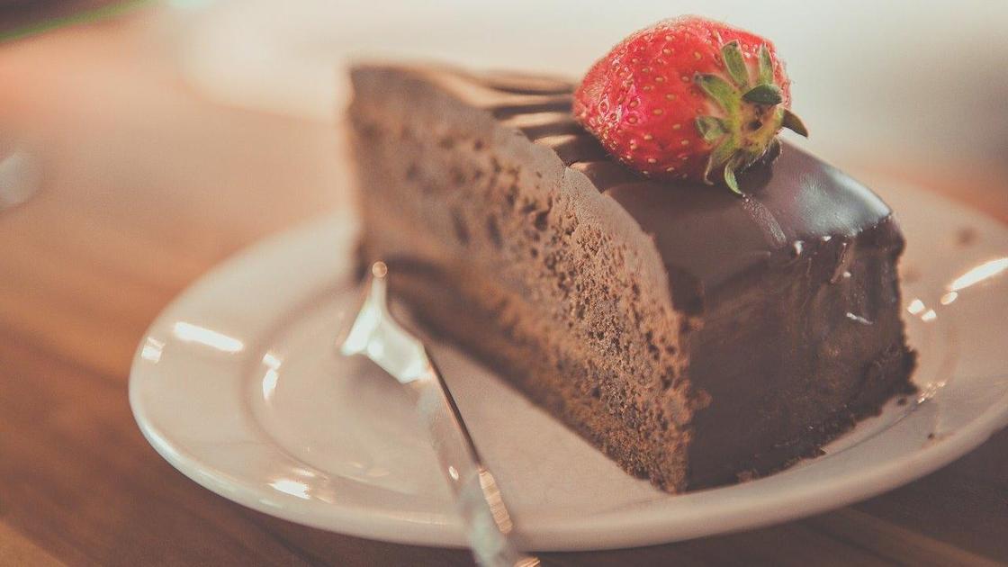 кусочек шоколадного торта с клубничкой на тарелке