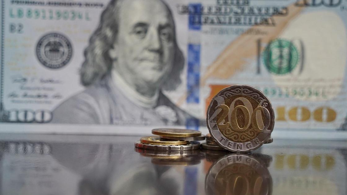Монеты тенге лежат на фоне доллара