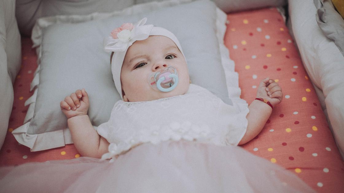 Новорожденная девочка лежит в кроватке
