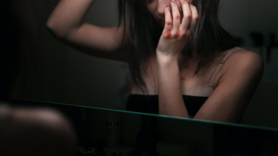 Девушка с синяками возле зеркала