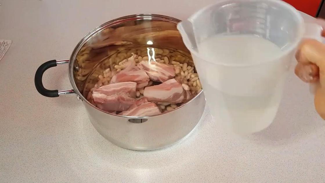 Фасоль и свинина в кастрюле с водой