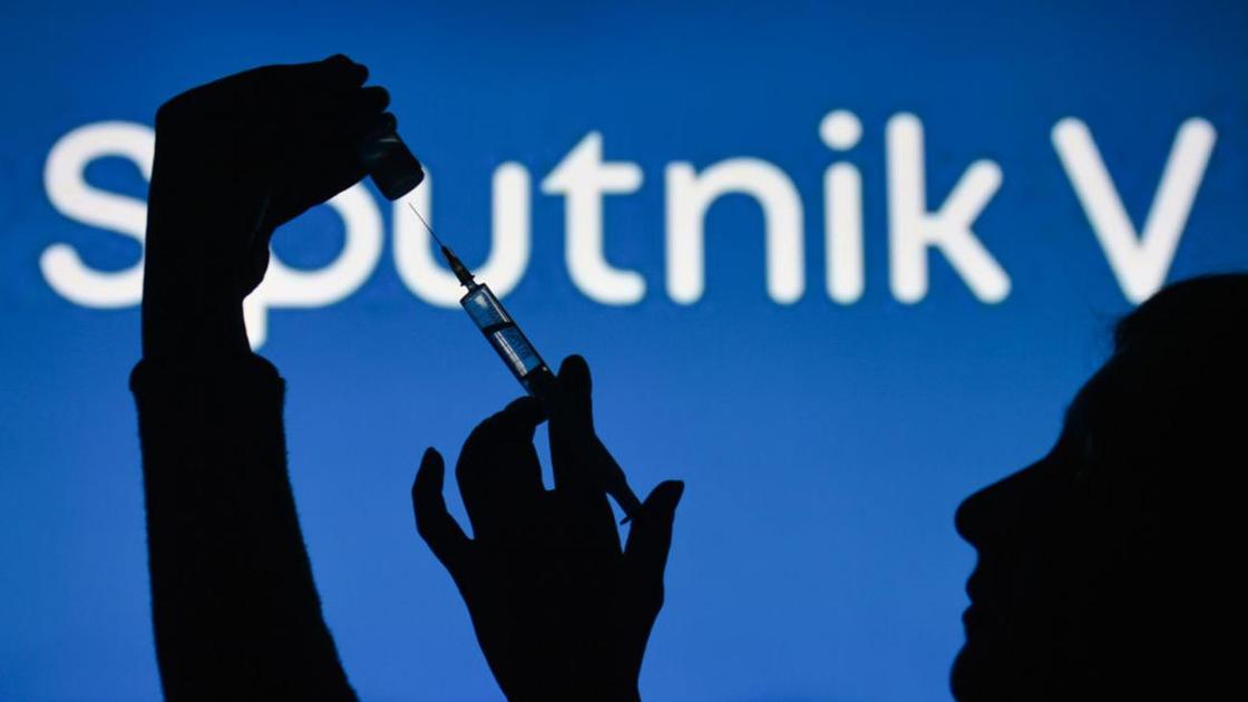 Женщина держит шприц с ампулой на фоне логотипа вакцины Sputnik V