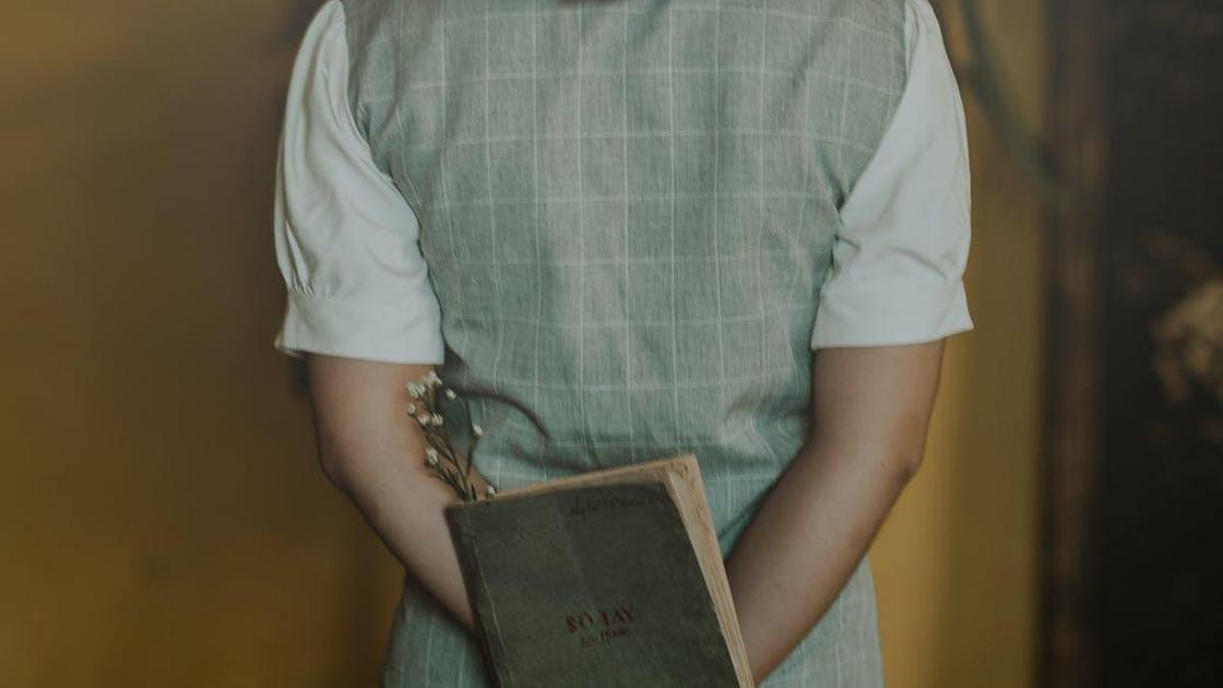 Девочка стоит спиной с книгой в руках