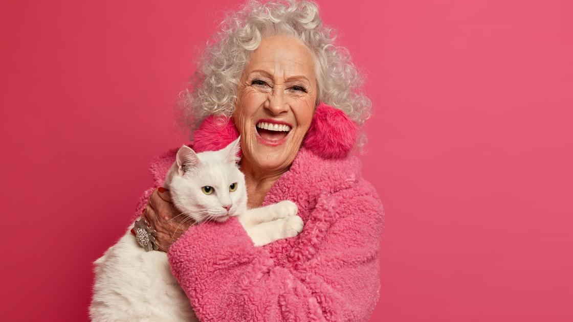 Пожилая женщина в розовом халате с котом