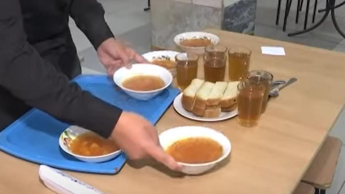 Тарелки с супом, ломтики хлеба и стаканы стоят на столе