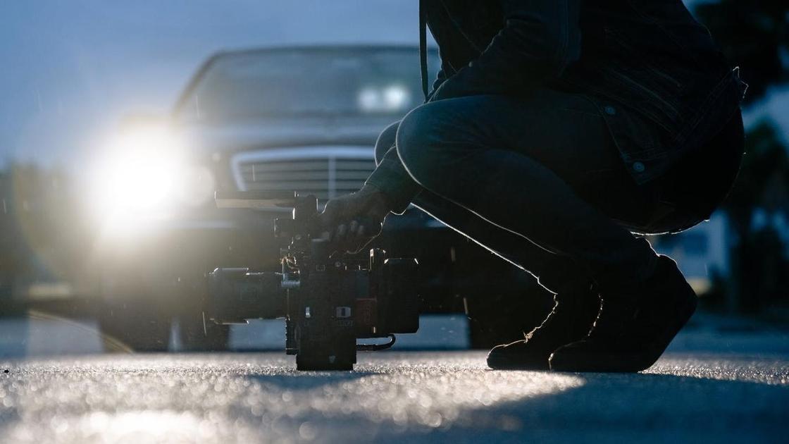 Мужчина снимает на камеру при свете автомобильных фар