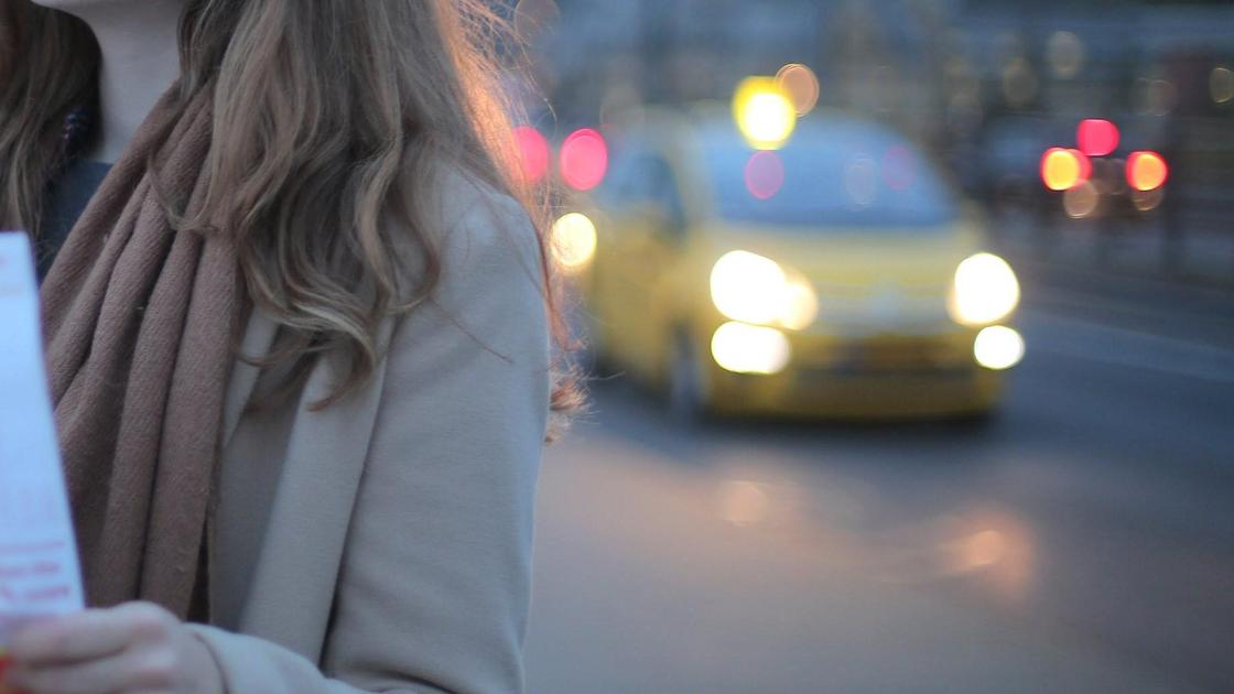 Девушка стоит на дороге спиной к такси