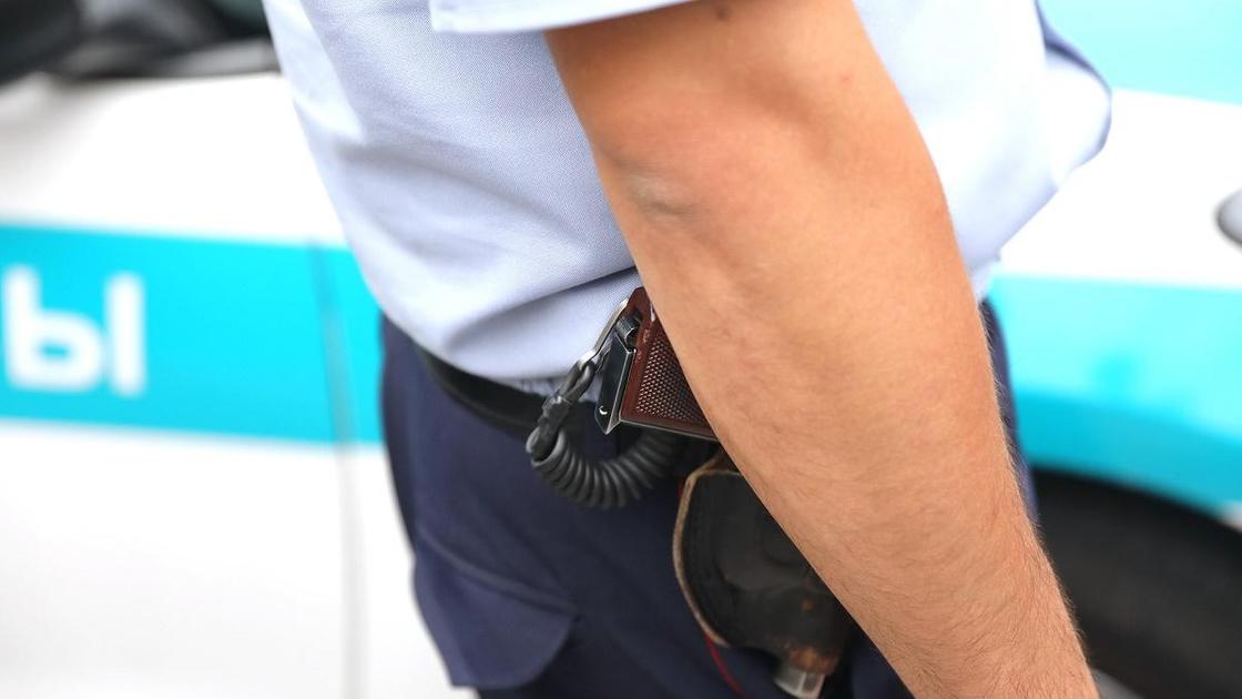 Полицейский в форме стоит с пистолетом в кобуре