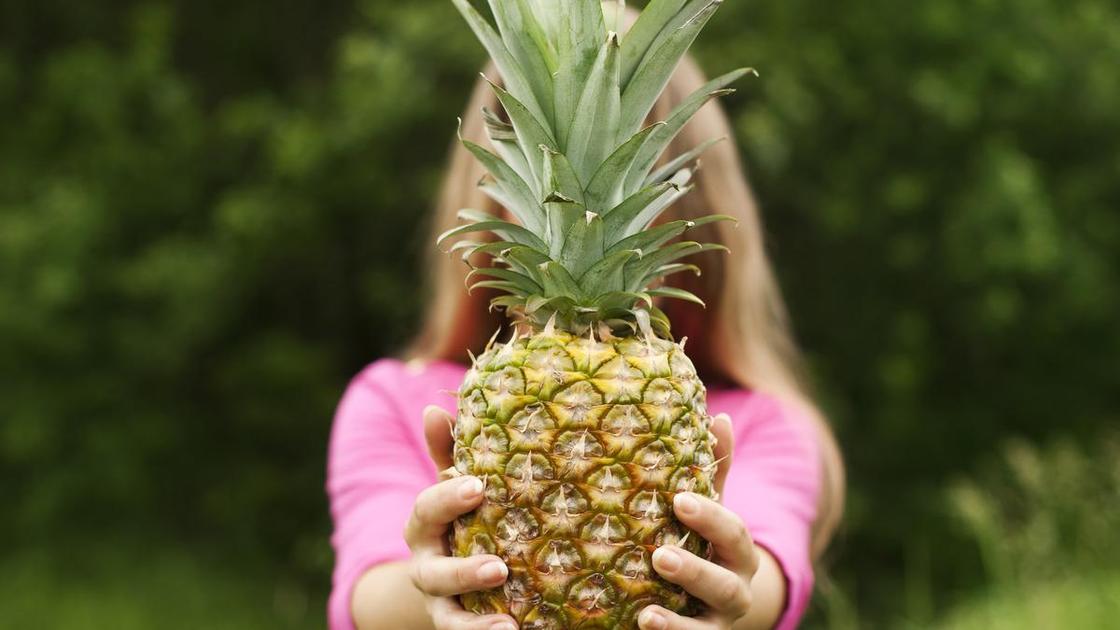 Девушка держит в руках большой ананас