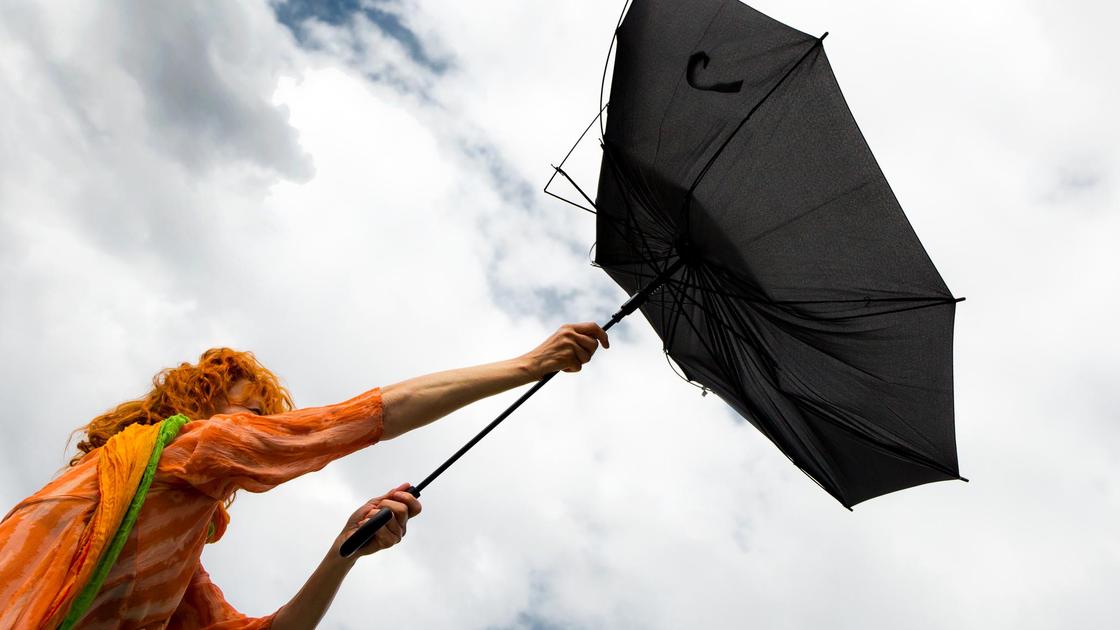 Женщина держит в руках зонт, поломанный ветром