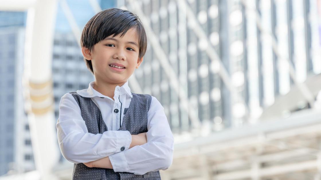 Корейский мальчик стоит на фоне небоскреба