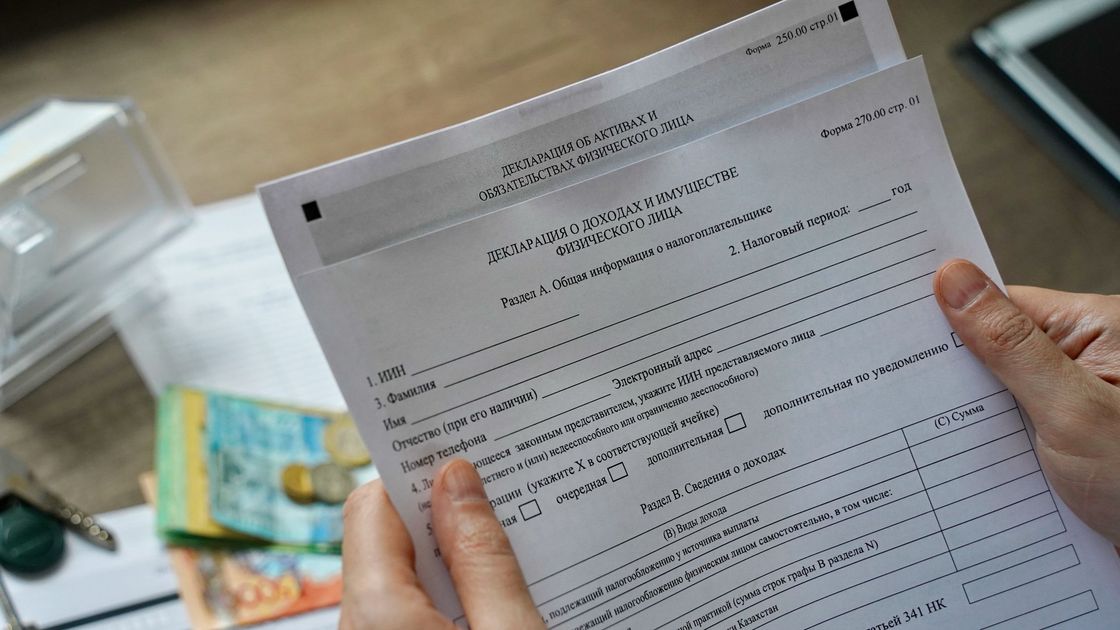 Казахстанец держит бланк для заполнения декларации о доходах и имуществе